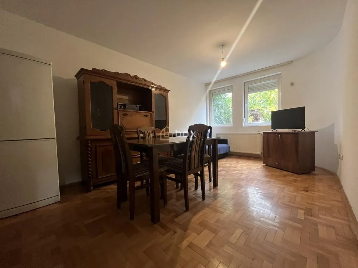 Living room with a dining table, wooden furniture, and parquet flooring.