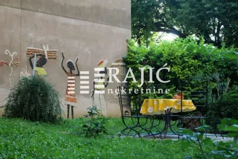 Dvorište zgrade sa stolom, stolicama i zidnim mozaikom. - image 17