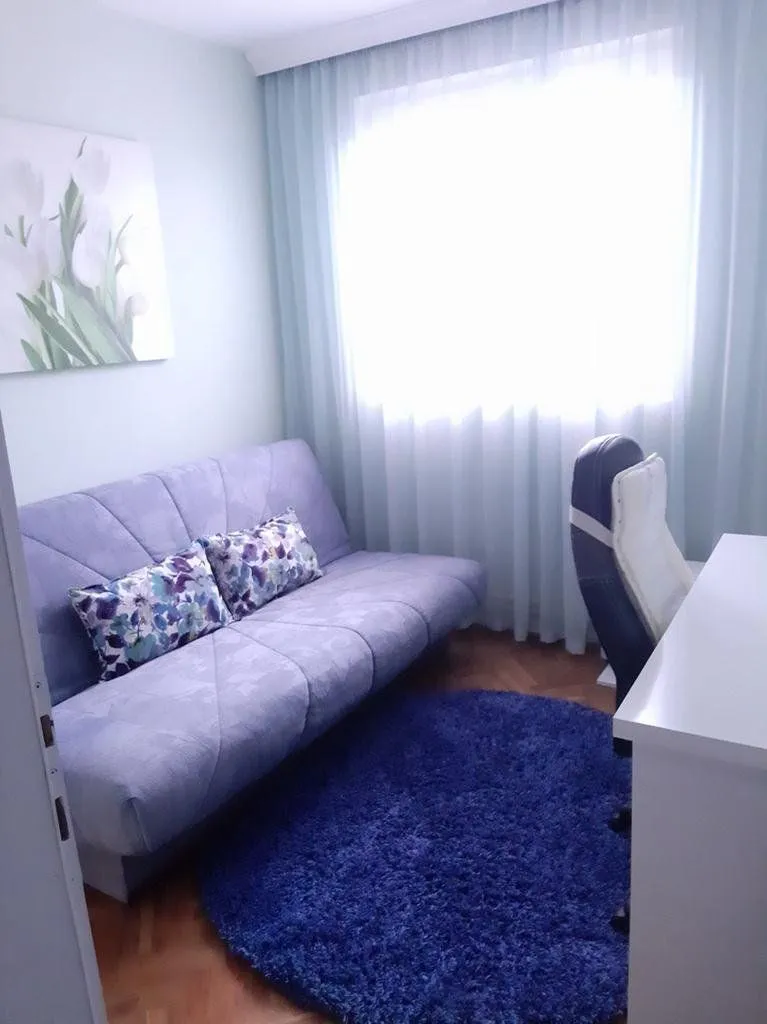 Small bedroom with a purple sofa and a desk.
