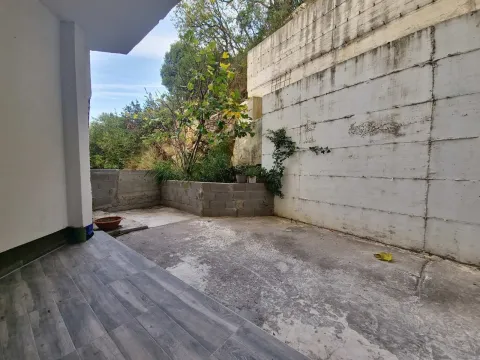 Paved courtyard with greenery and a high concrete wall. - image 6