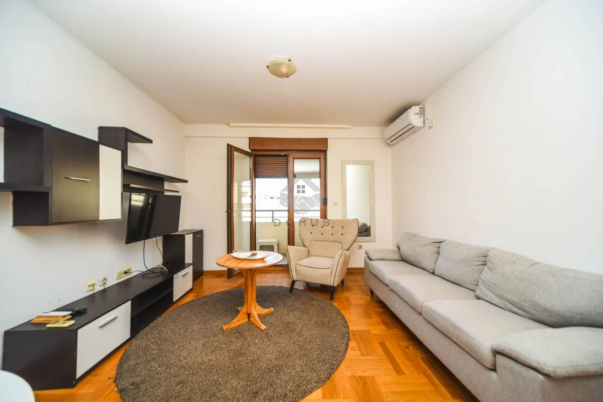Living room with a sofa, TV, and access to the balcony.