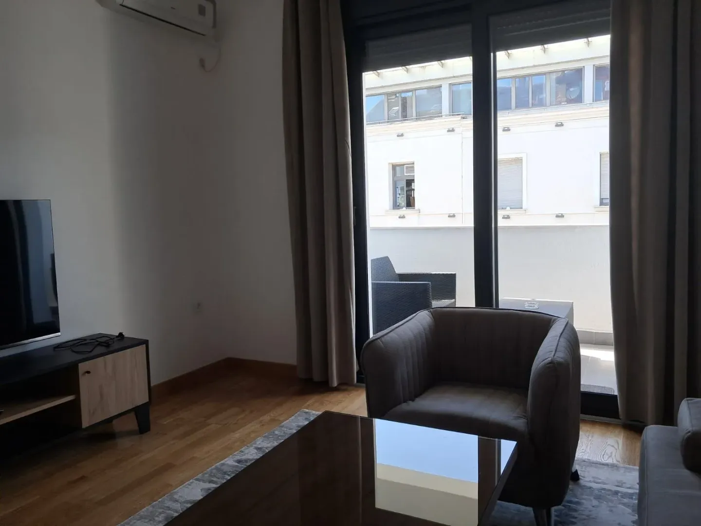 Living room with an armchair, television, and terrace access.