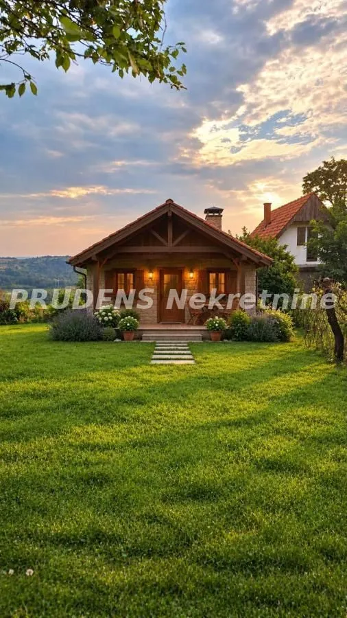 Pogled na dvorište i fasadu prizemne kamene kuće sa uređenim travnjakom.