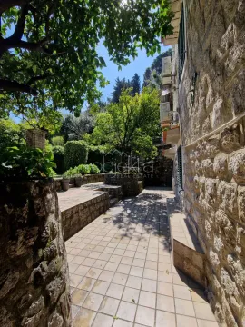 Tiled courtyard with greenery next to a stone house. - image 5