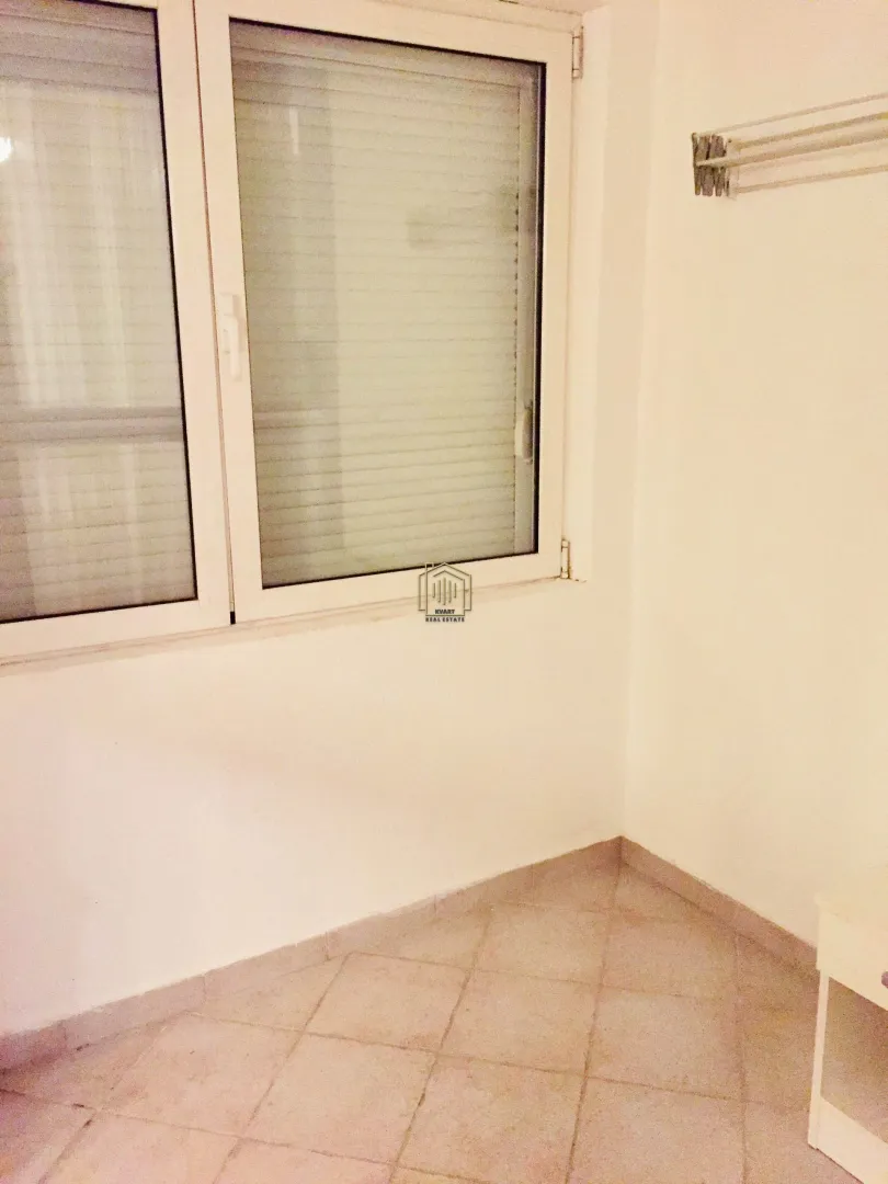 Prazna prostorija sa prozorom i keramičkim pločicama na podu.