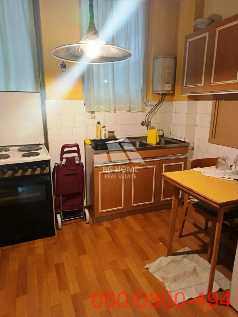 Starija kuhinja sa trpezarijskim stolom i kuhinjskim elementima.