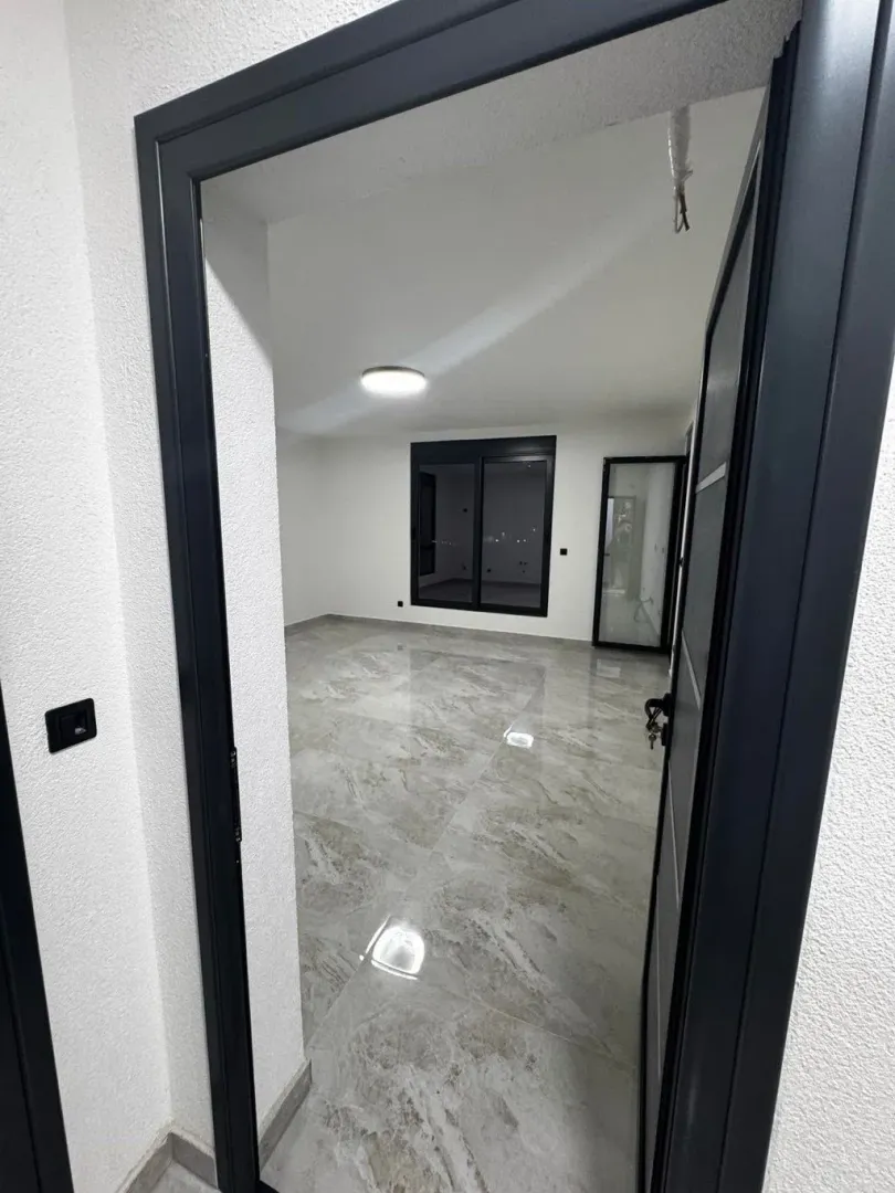 View through the doorway into an empty room with tiled flooring.