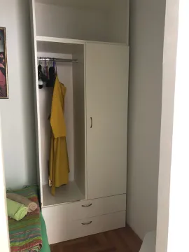 Small white wardrobe with an open section and hangers in the room. - image 11