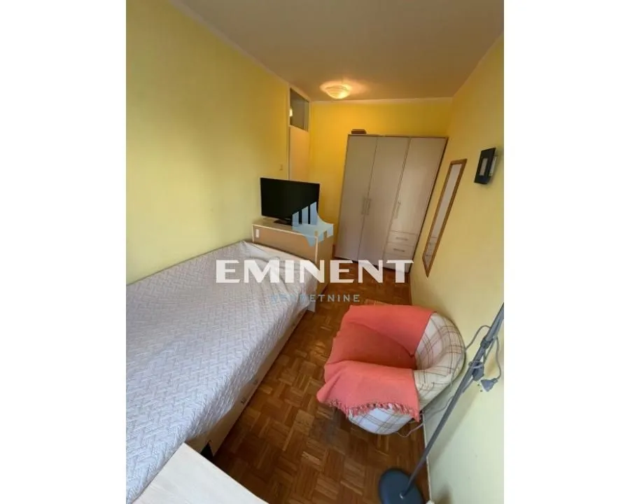 Furnished bedroom with a bed, wardrobe, and TV.