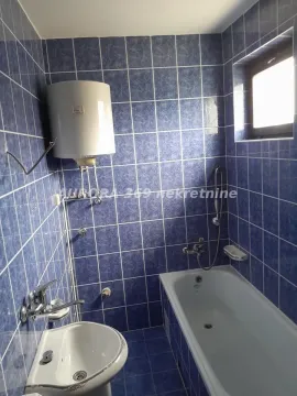 Kupatilo obloženo plavim pločicama sa kadom, umivaonikom i bojlerom. - image 9