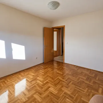 Prazna prostorija sa parketom i otvorenim drvenim vratima. - image 7