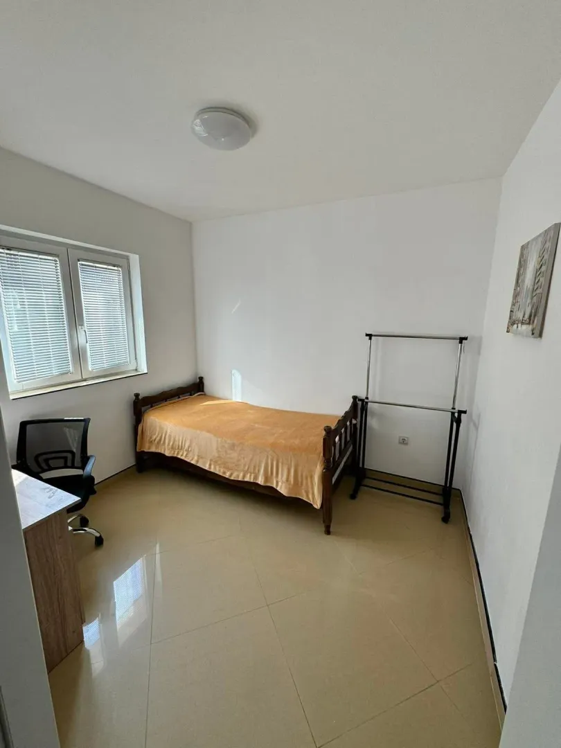 Small bedroom with a bed, desk, and a window.