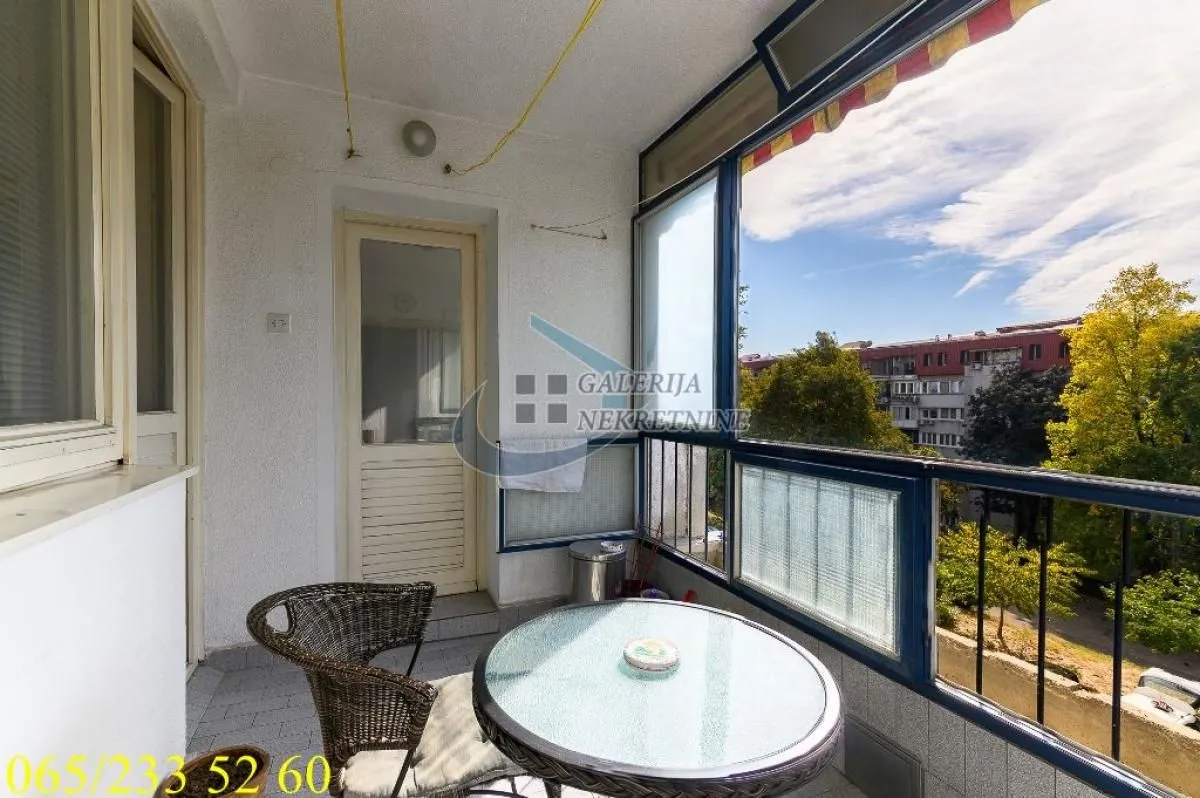 Zastakljeni balkon sa stočićem i stolicom.