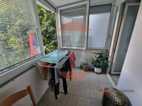 Zastakljeni balkon sa sušilicom za veš i zelenilom u pozadini. - image 8