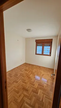 Prazna soba sa parketom i prozorom koji gleda na zgrade. - image 13