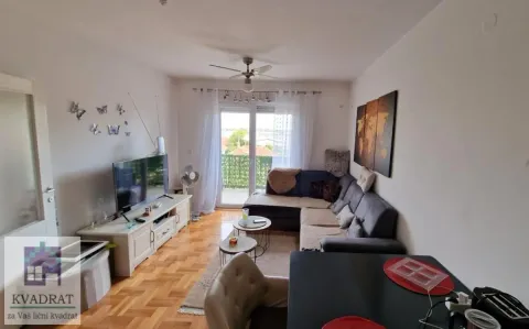 Nameštena dnevna soba sa garniturom, televizorom i izlazom na terasu. - image 2