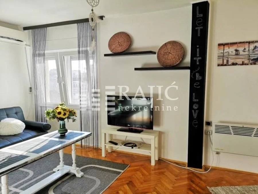 Living room with a sofa, TV, and dining table.