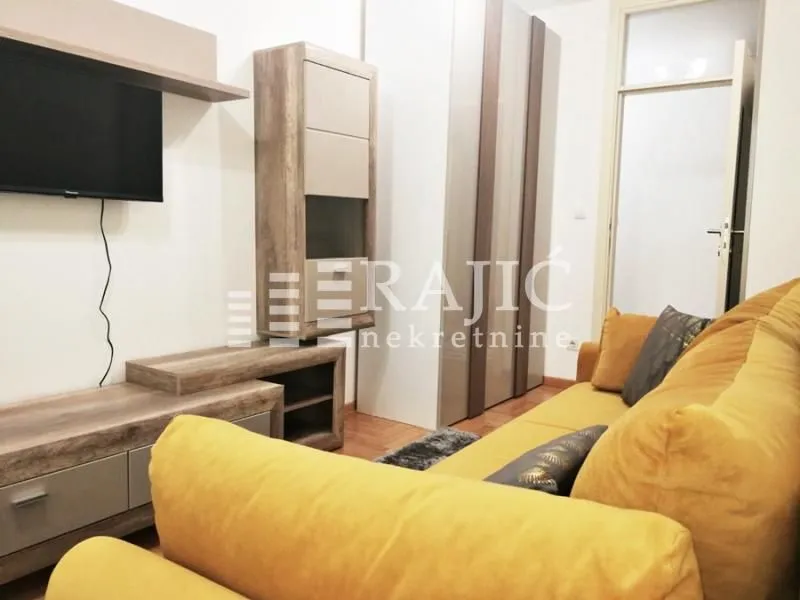 Living room with sofa, TV unit, and wardrobes.