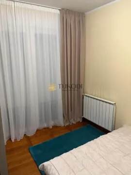 Manja spavaća soba sa krevetom, prozorom sa zavesama i radijatorom. - image 8