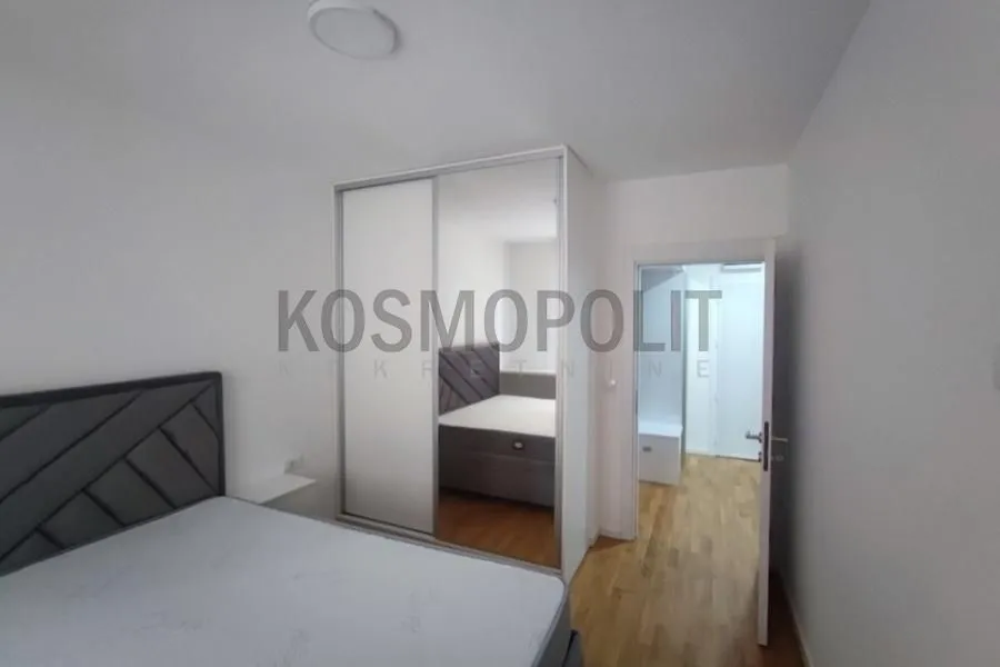 Spavaća soba sa bračnim krevetom i velikim ugradnim plakarom sa ogledalom.