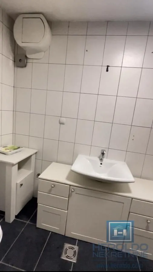 Kupatilo sa belim umivaonikom i belim elementima.