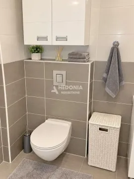 Moderno uređeno kupatilo sa WC šoljom, ormarićem i detaljima u sivim tonovima. - image 12