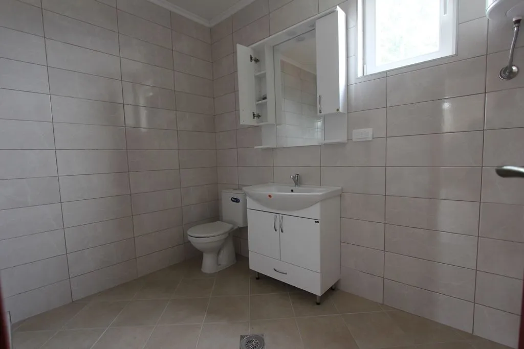 Bright bathroom with white fixtures and ceramic tiles.