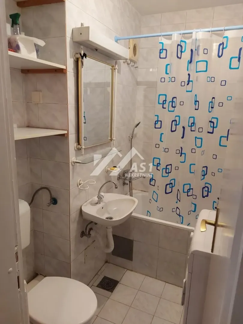 Manje kupatilo sa kadom, umivaonikom, ogledalom i toaletom.