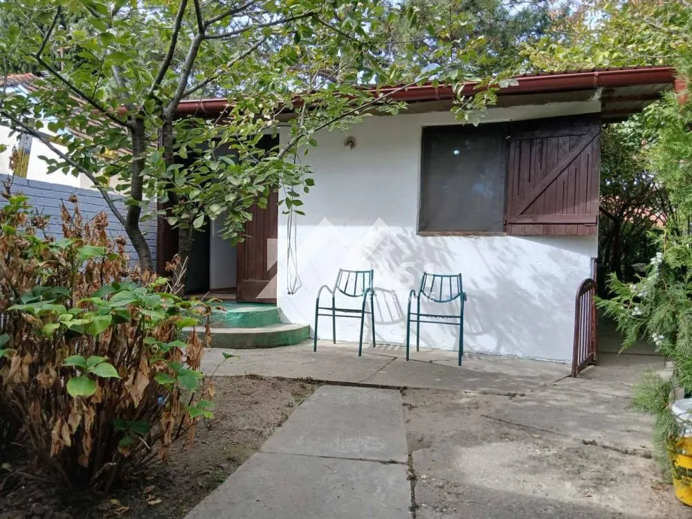 Pogled na dvorište i fasadu kuće sa stazom i baštenskim nameštajem.