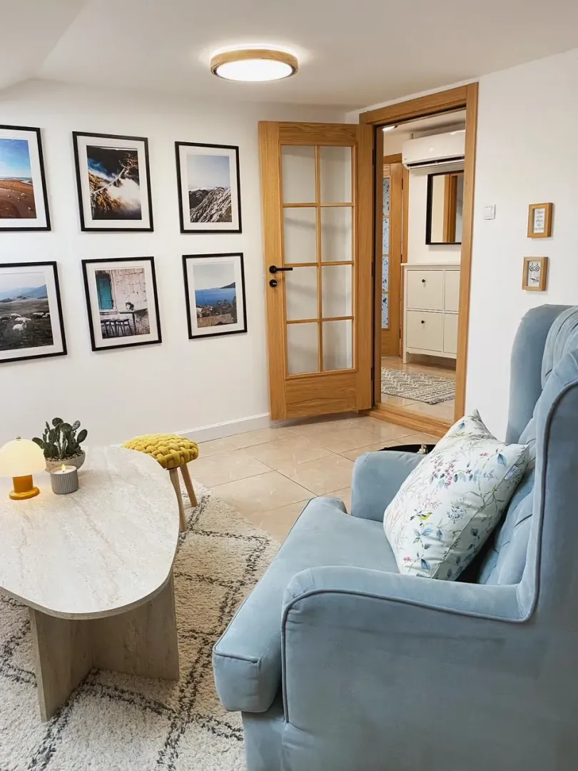Cozy living room with an armchair, coffee table, and framed pictures on the wall.