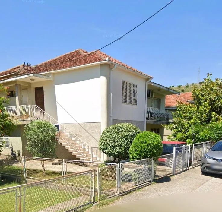 Spoljašnji pogled na dvorište i fasadu kuće sa spoljnim stepeništem.
