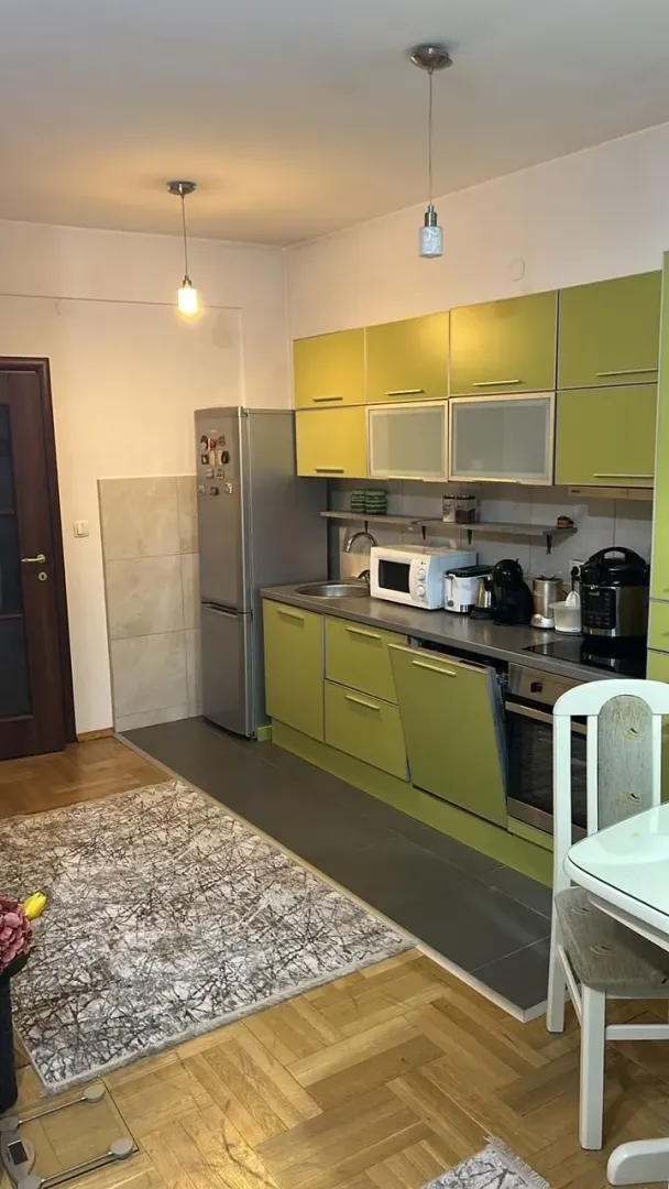 Kuhinja u zelenim tonovima sa radnim elementima i bijelom tehnikom.