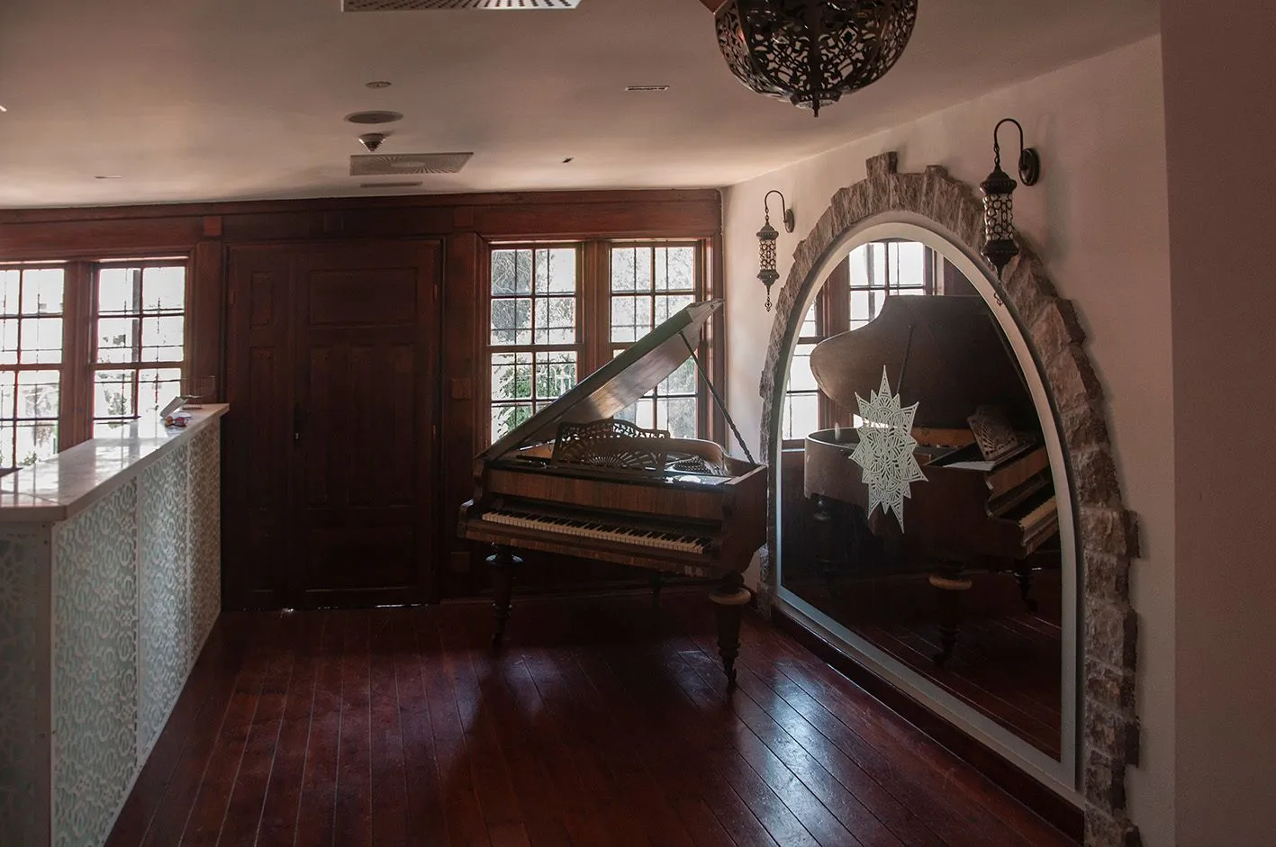 Spacious living room with a piano and a large mirror in a stone frame.