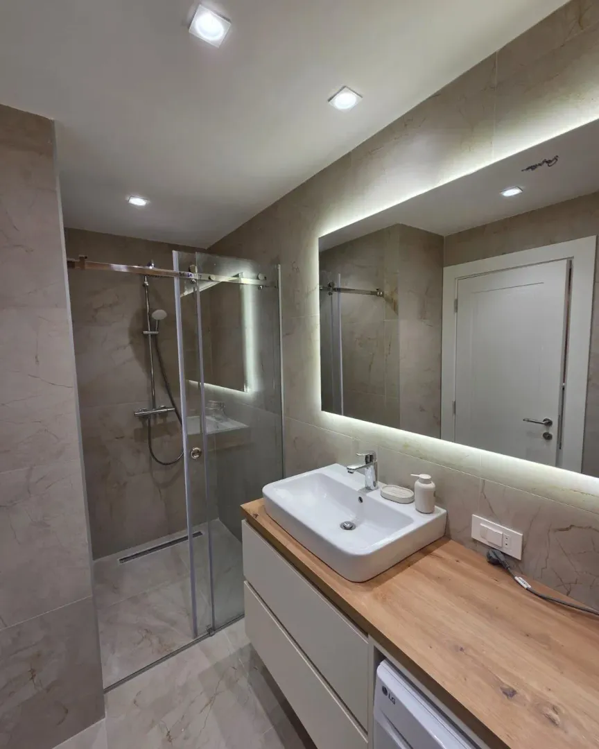 Modern bathroom equipped with a walk-in shower and a sink on a wooden countertop.