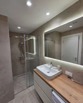 Modern bathroom equipped with a walk-in shower and a sink on a wooden countertop. - image 11