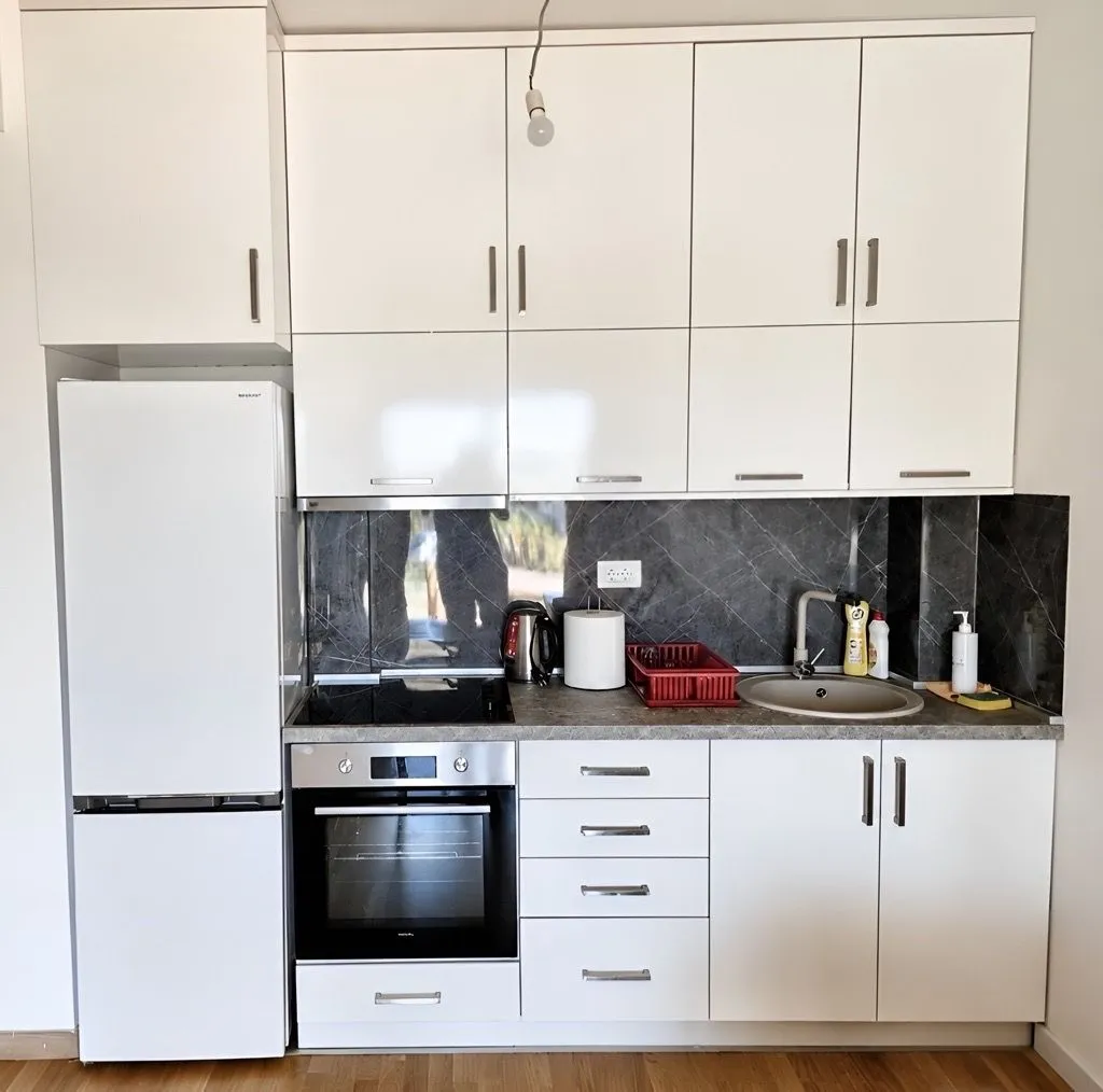 A view of a bright kitchen with white cabinets, a refrigerator, and built-in appliances.