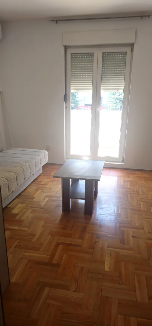 Dnevna soba sa parketom, garniturom i izlazom na terasu.