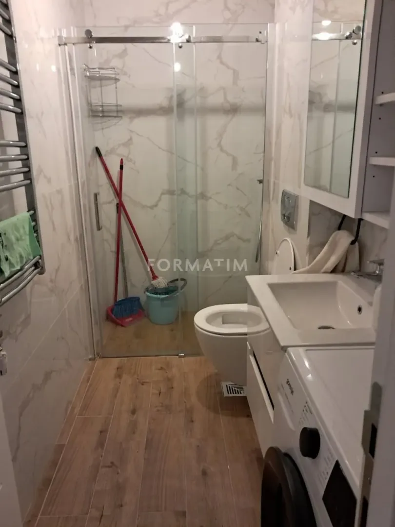 Small bathroom with a shower cabin, washbasin, and washing machine.