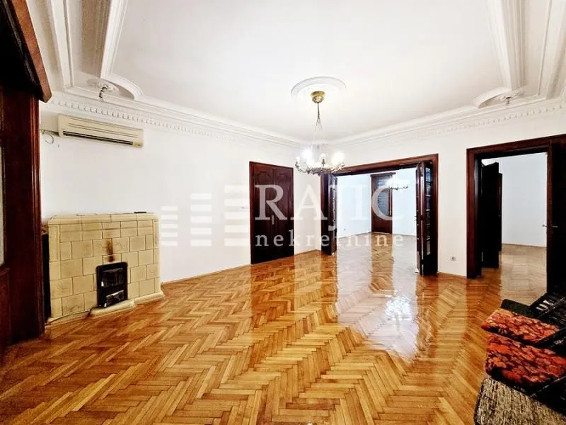 Spacious living room with wooden parquet flooring, a wood-burning stove, and traditional ceiling moldings.