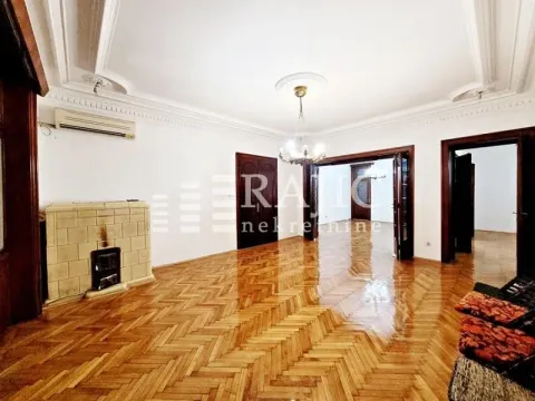 Spacious living room with wooden parquet flooring, a wood-burning stove, and traditional ceiling moldings. - image 2