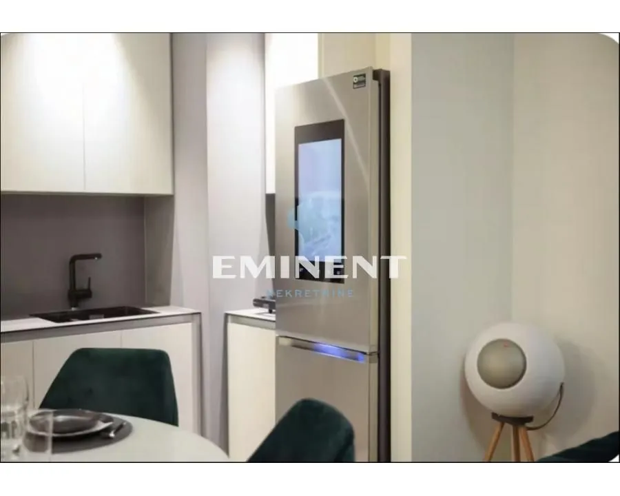 A view of a modern equipped kitchen with a refrigerator and a dining table.