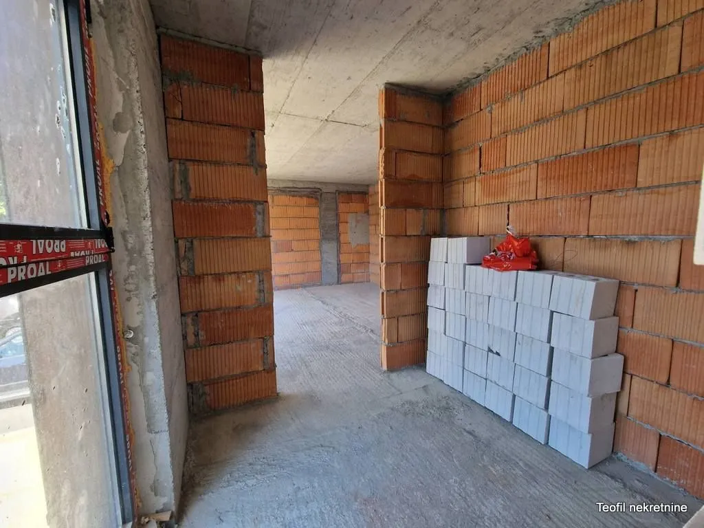 Pogled na nenamješten prostor u izgradnji sa zidovima od cigle i blokova.