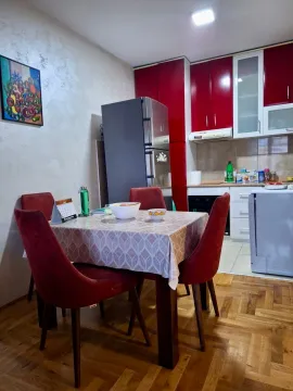 Trpezarijski sto sa stolicama u kuhinji sa crvenim elementima. - image 3
