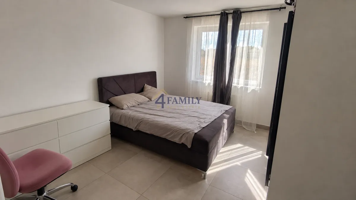 Furnished bedroom with a double bed, white dresser, and a window.