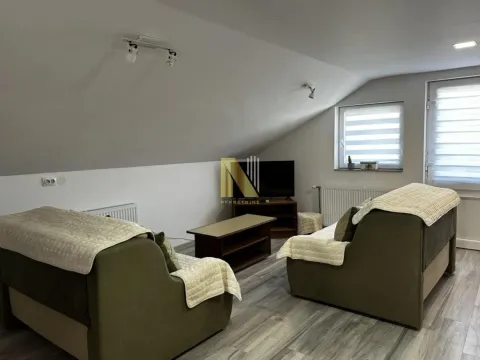 Dnevna soba u potkrovlju sa garniturom za sedenje i televizorom. - image 2