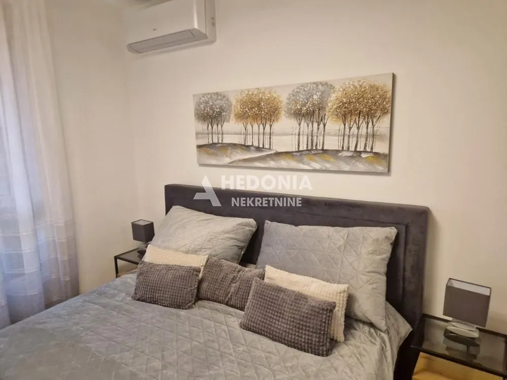 Furnished bedroom with a double bed, bedside tables, and an air conditioner.