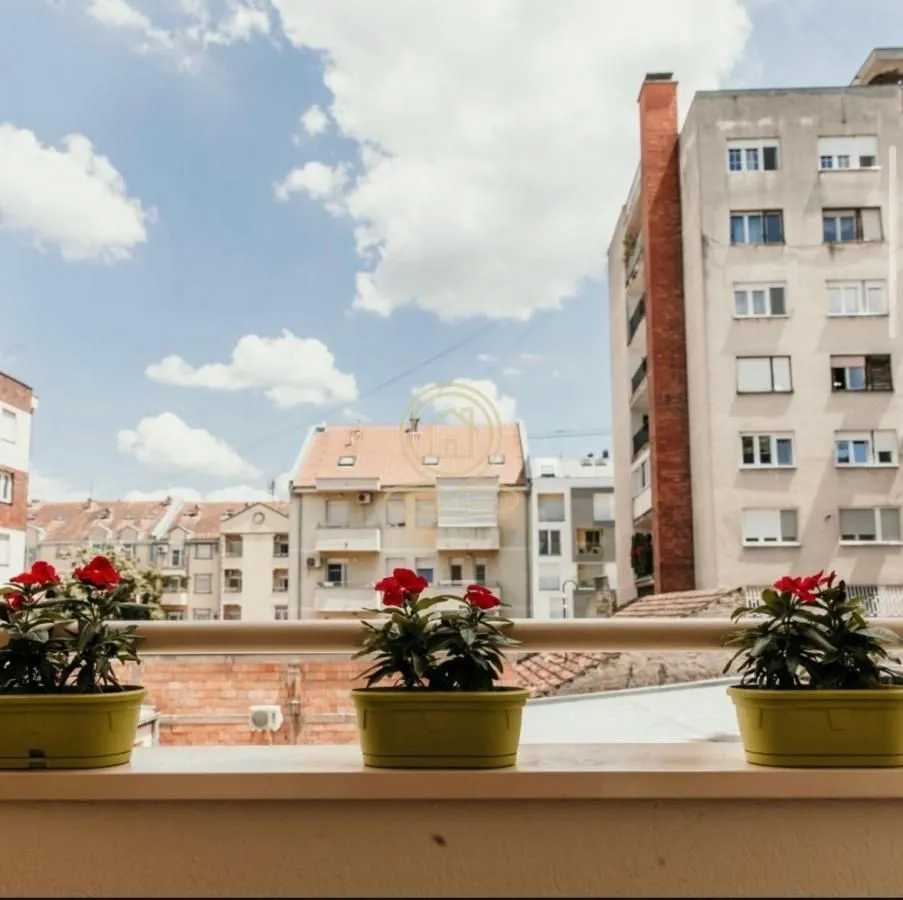 Pogled sa balkona na okolne zgrade i gradski pejzaž.