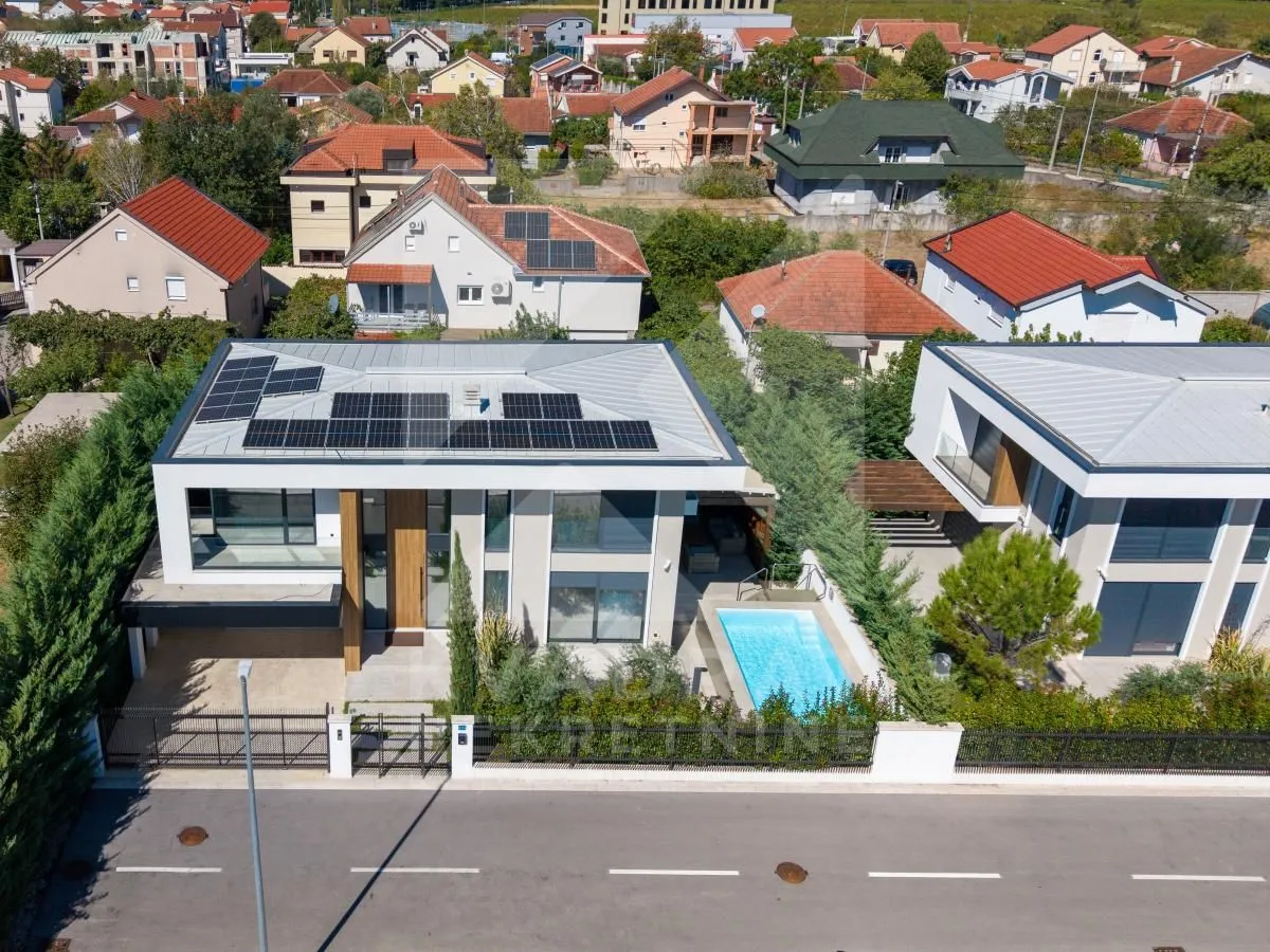 Aerial view of a modern villa with a swimming pool and rooftop solar panels.