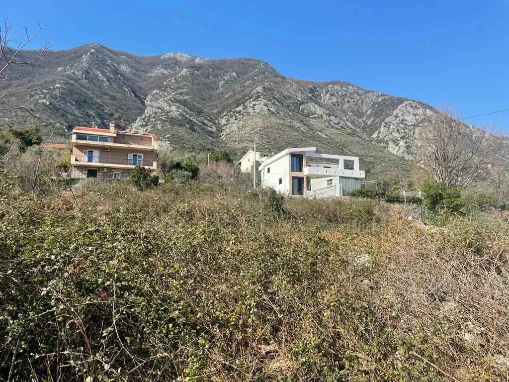 Kuće na brdu okružene zelenilom podno planine.