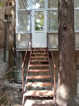 Spoljni ulaz sa metalnim stepenicama koje vode do vrata objekta. - image 6